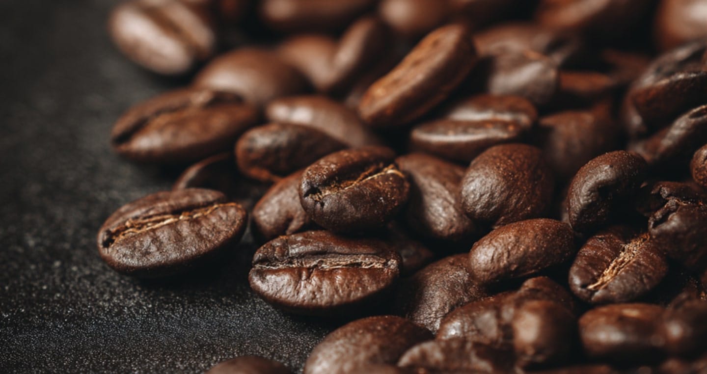 Ziarna palonej kawy na ciemnym tle.
