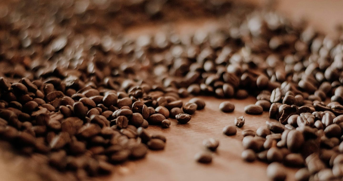 Rozsypane palone ziarna kawy na drewnianym stole.