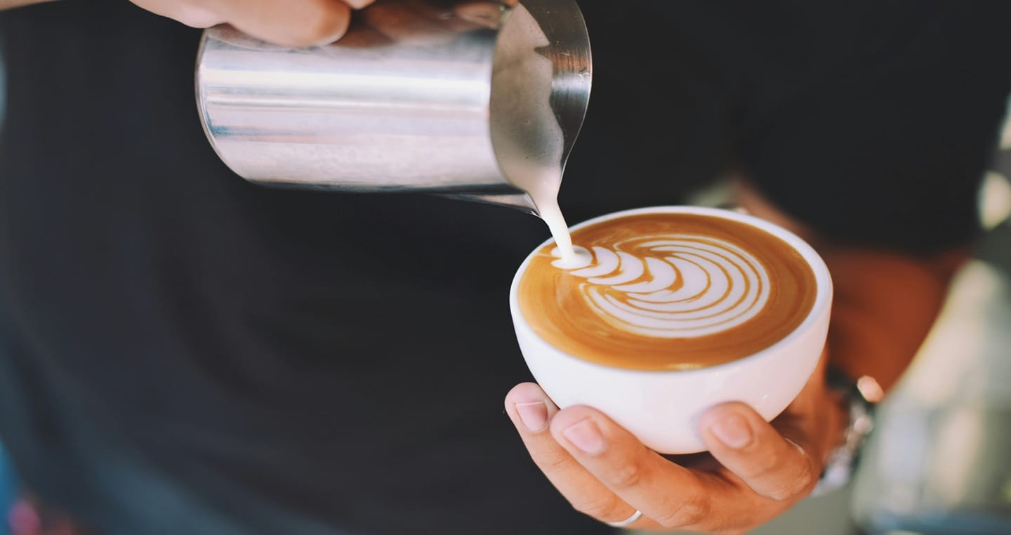 Nalewanie mleka do filiżanki kawy, wzór latte art.