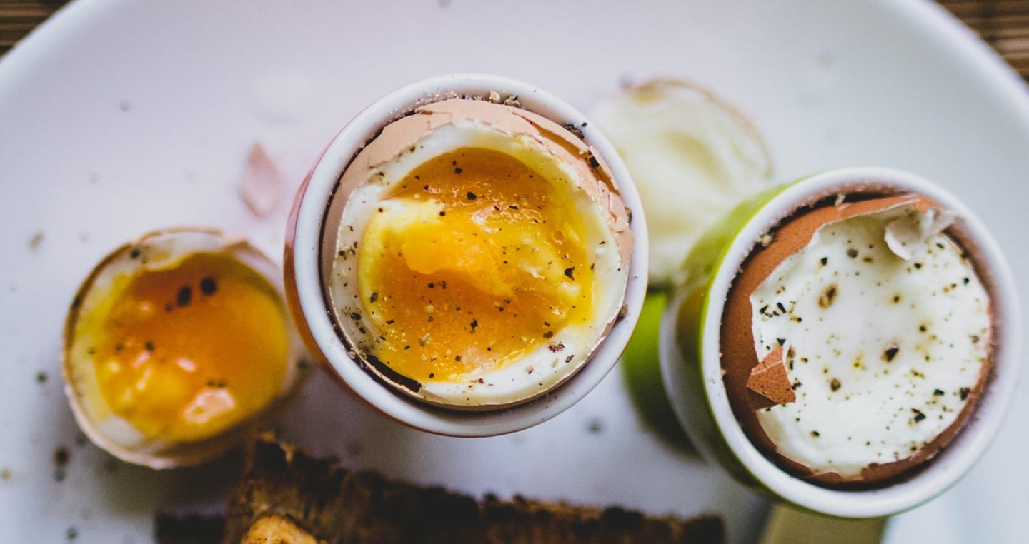 Trzy jajka na miękko z pieprzem na talerzu.