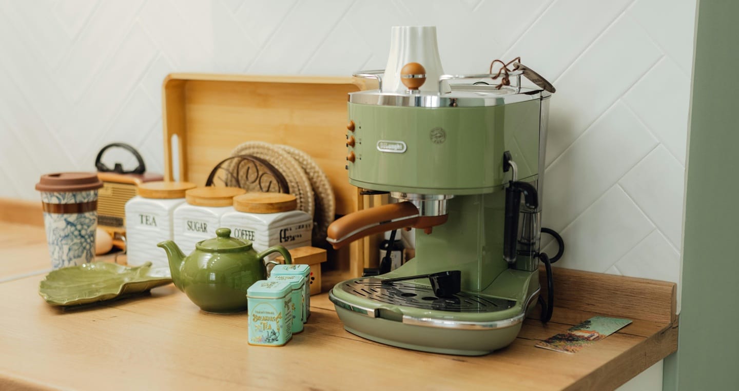 Zielony ekspres do kawy na blacie z pojemnikami na herbatę, cukier i kawę.