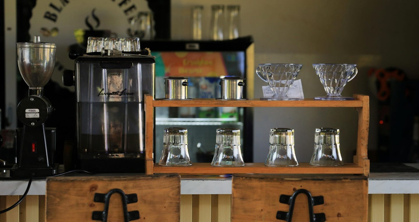 Ekspres do kawy, młynek, drippery i odwrócone szklanki na blacie w kawiarni.