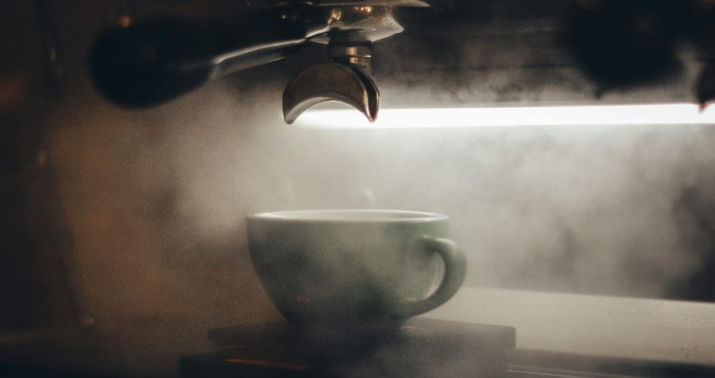 Urządzenia do parzenia kawy i ekspres ciśnieniowy w tle.