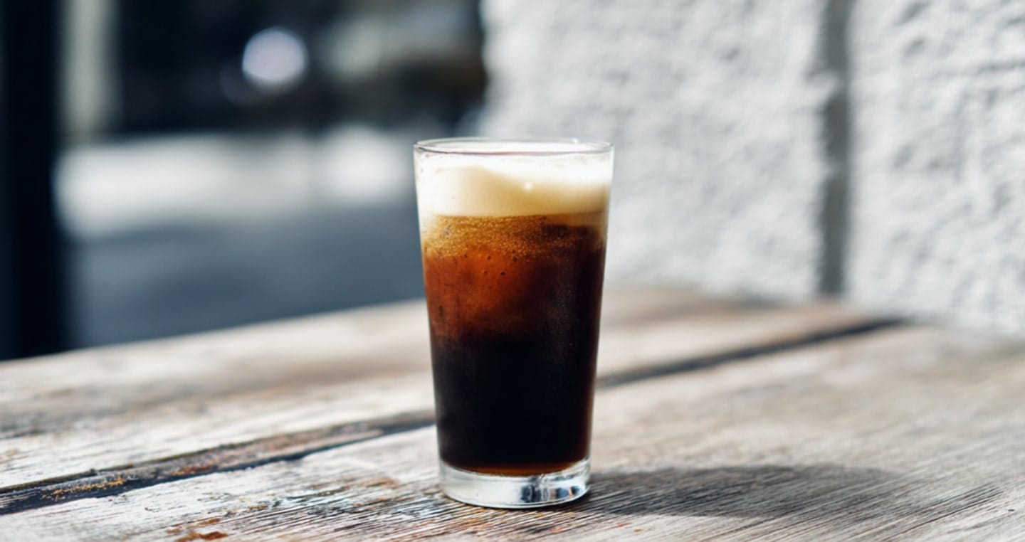 Szklanka zimnego nitro cold brew na drewnianym stole.