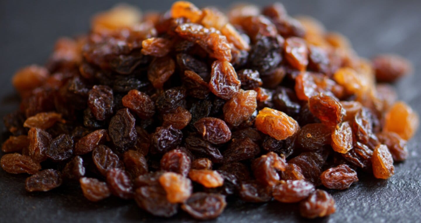 Suszone rodzynki ułożone na czarnej powierzchni.