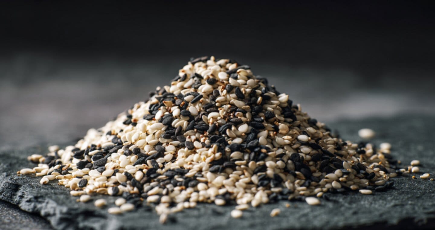 Stos nasion sezamu, białych i czarnych, na ciemnym tle.