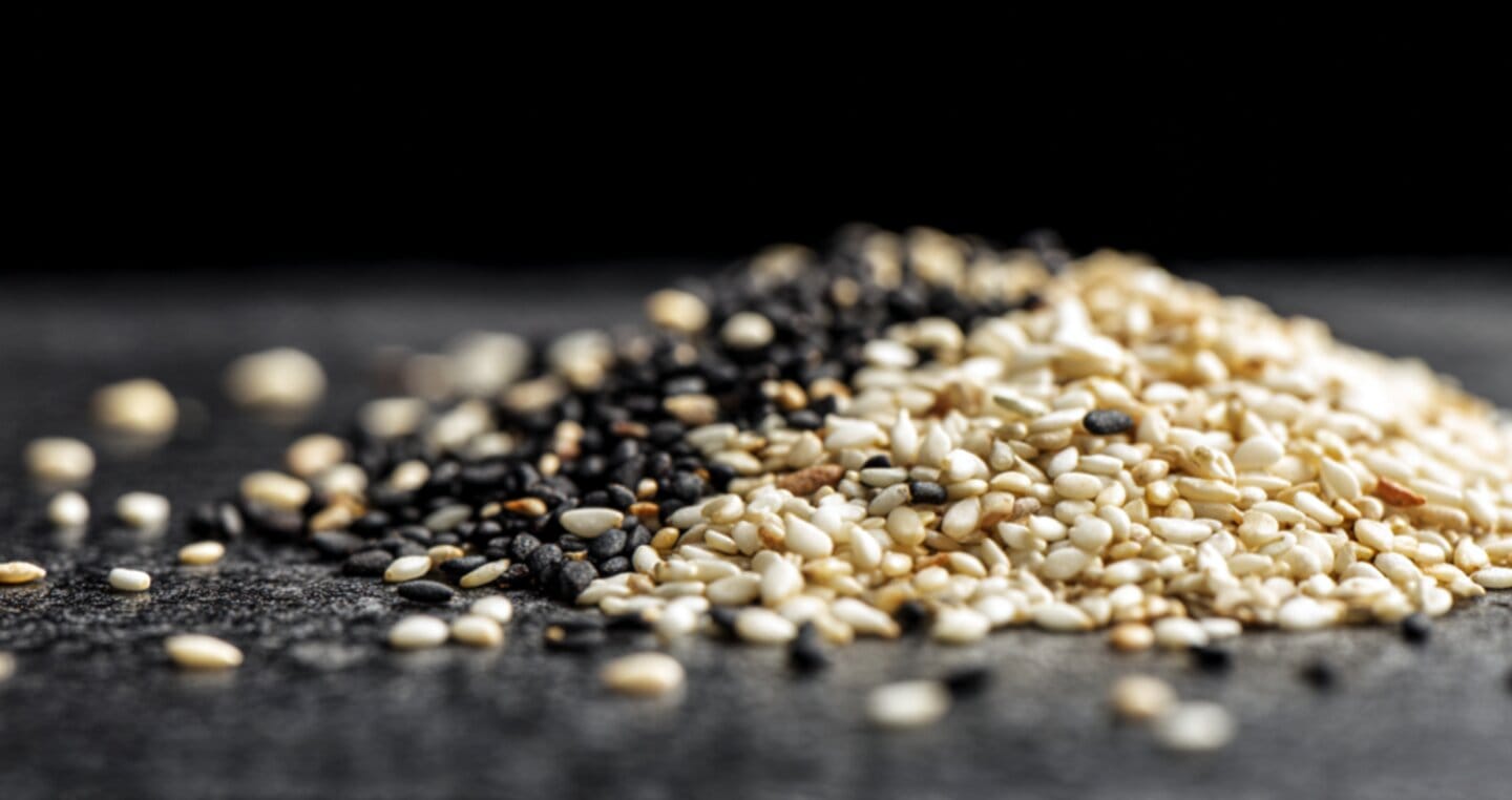 Białe i czarne nasiona sezamu na ciemnym tle.