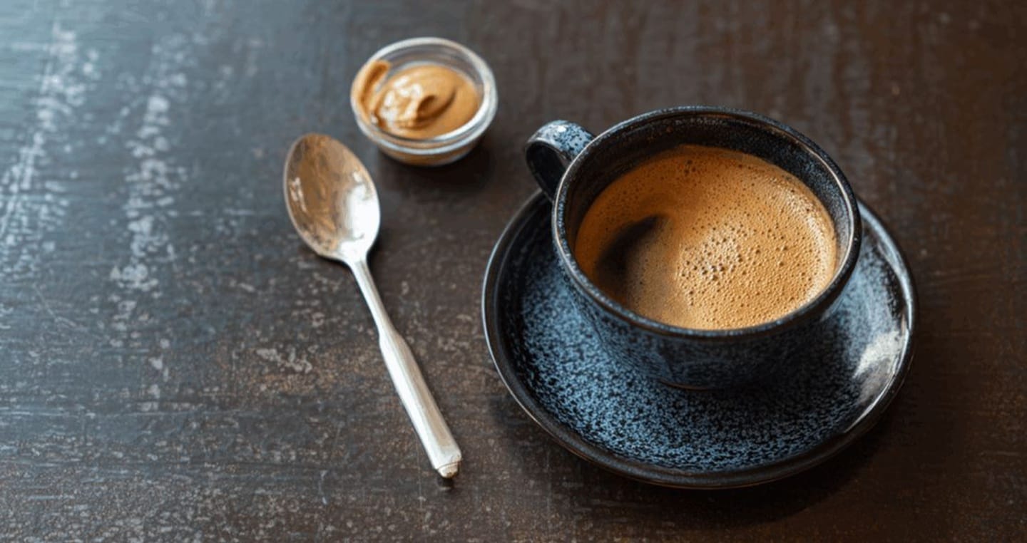 kawa w niebieskiej filiżance z łyżeczką na drewnianym stole