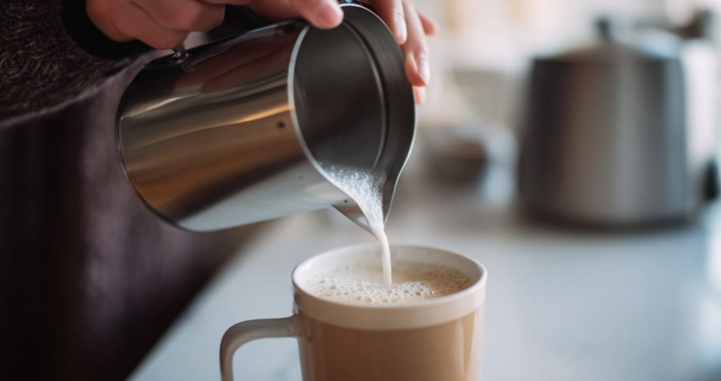 Nalewanie spienionego mleka do filiżanki cappuccino.